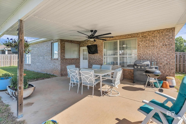 view of patio with a ceiling fan, outdoor dining space, fence, exterior kitchen, and grilling area