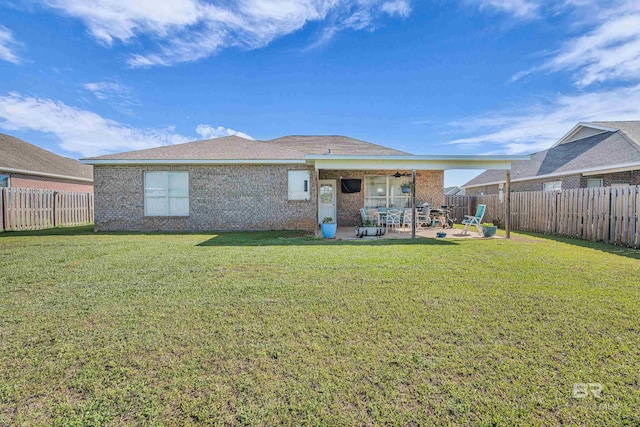 back of house featuring a lawn, a patio area, brick siding, and a fenced backyard