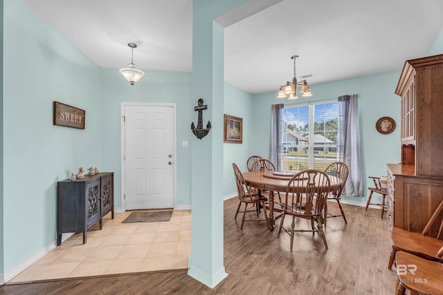 dining space featuring light wood-style floors, a chandelier, baseboards, and visible vents