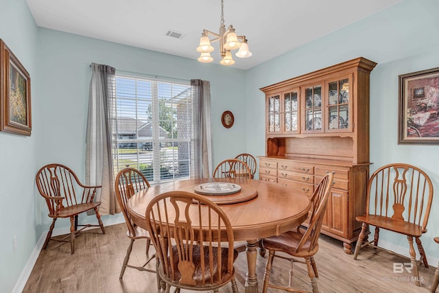 dining area featuring light wood-type flooring, a notable chandelier, visible vents, and baseboards
