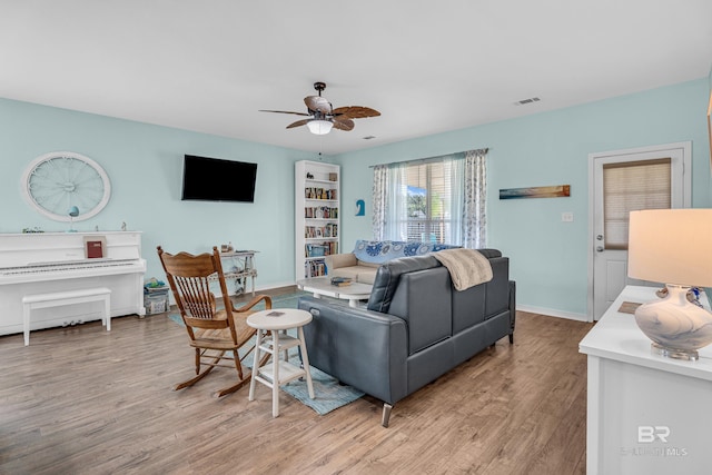 living area featuring baseboards, light wood finished floors, ceiling fan, and visible vents