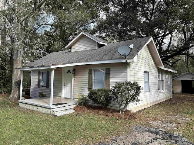 view of front facade with covered porch, a storage shed, and a front lawn