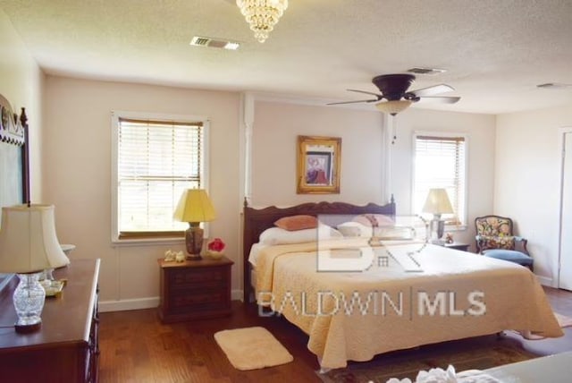 bedroom with a textured ceiling, multiple windows, dark hardwood / wood-style floors, and ceiling fan