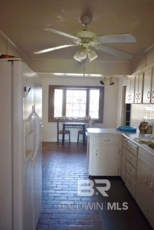 kitchen with kitchen peninsula, white cabinets, white refrigerator with ice dispenser, and ceiling fan