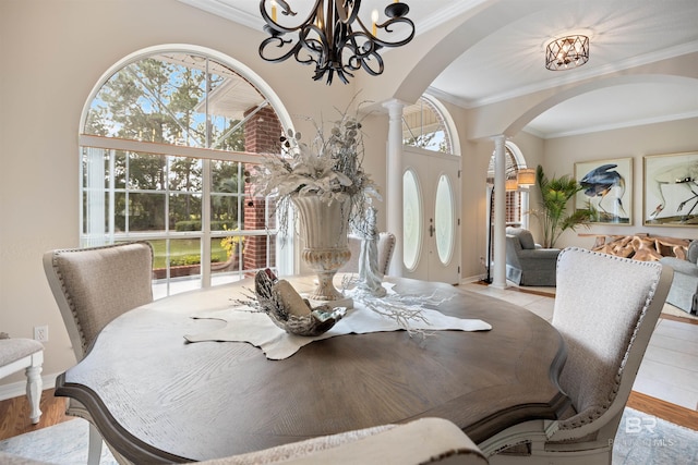 dining space with ornamental molding, decorative columns, and light hardwood / wood-style floors