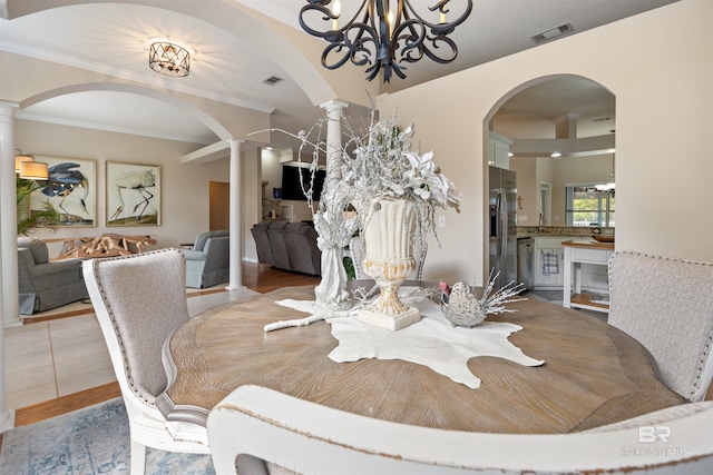 dining room with light hardwood / wood-style floors, ornate columns, and crown molding