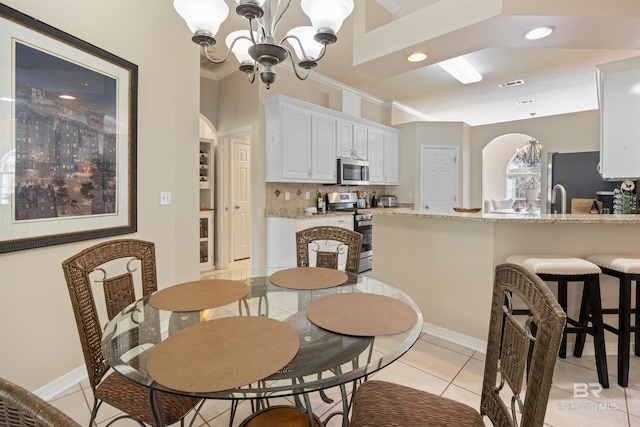 tiled dining room with ornamental molding, sink, and a chandelier