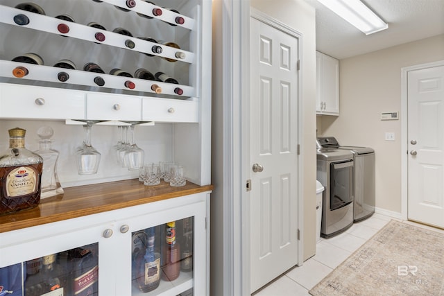 washroom with cabinets, light tile patterned floors, a textured ceiling, and separate washer and dryer