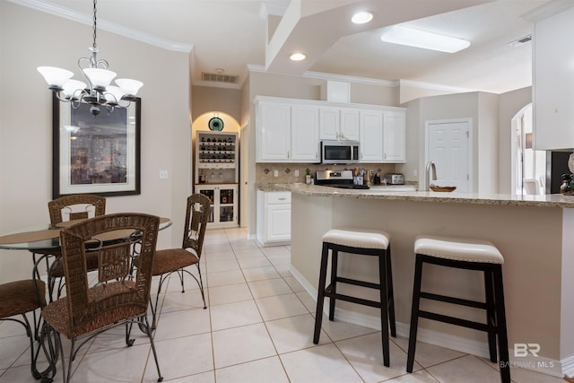 kitchen featuring white cabinets, a notable chandelier, light stone counters, and appliances with stainless steel finishes