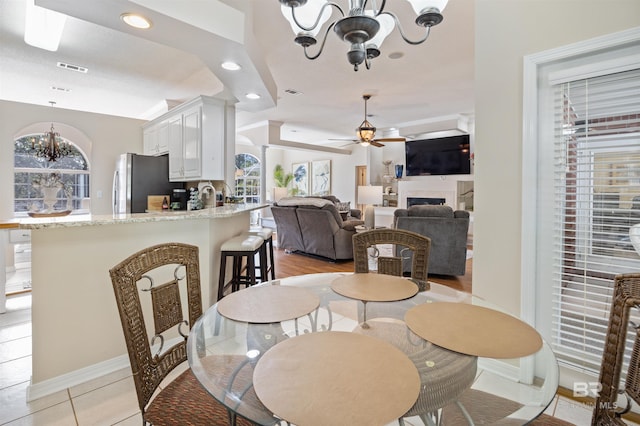 dining room with light tile patterned flooring and ceiling fan with notable chandelier