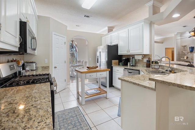 kitchen with sink, light stone countertops, a textured ceiling, white cabinetry, and stainless steel appliances