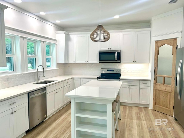 kitchen with sink, stainless steel appliances, white cabinetry, and pendant lighting