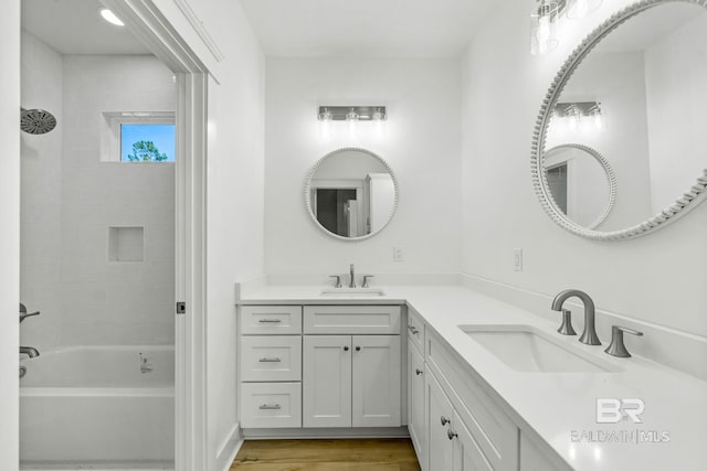 bathroom with hardwood / wood-style flooring, tiled shower / bath combo, and vanity