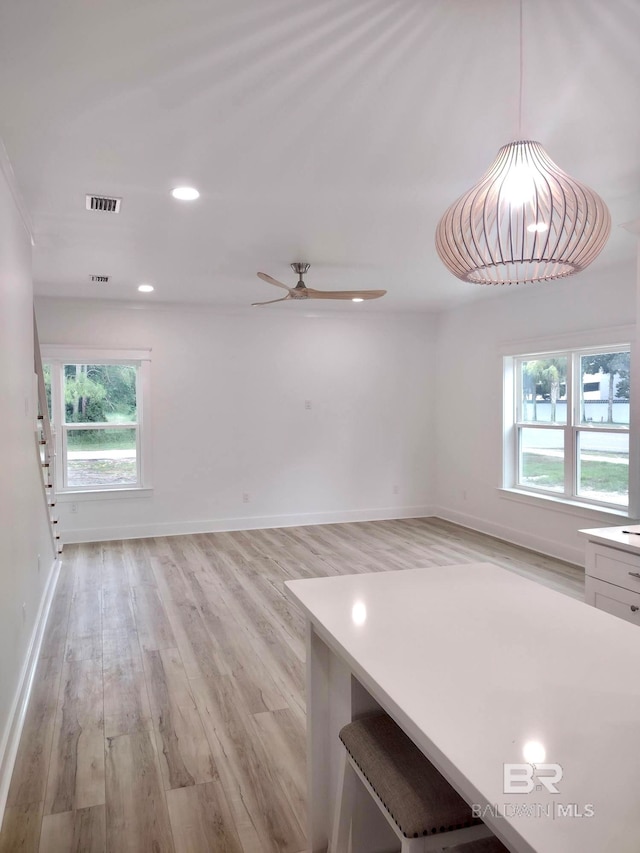 interior space with light wood-type flooring, ceiling fan, a healthy amount of sunlight, and hanging light fixtures