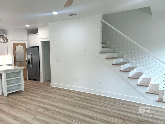 interior space featuring light wood-type flooring, ceiling fan, white cabinetry, and stainless steel refrigerator with ice dispenser