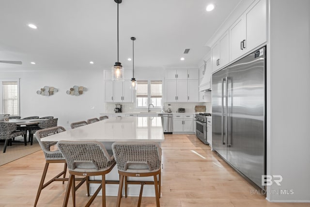 16761 Perdido Key Dr, Pensacola, FL 32507 - kitchen with light wood-type flooring, a center island, white cabinetry, hanging light fixtures, and high quality appliances