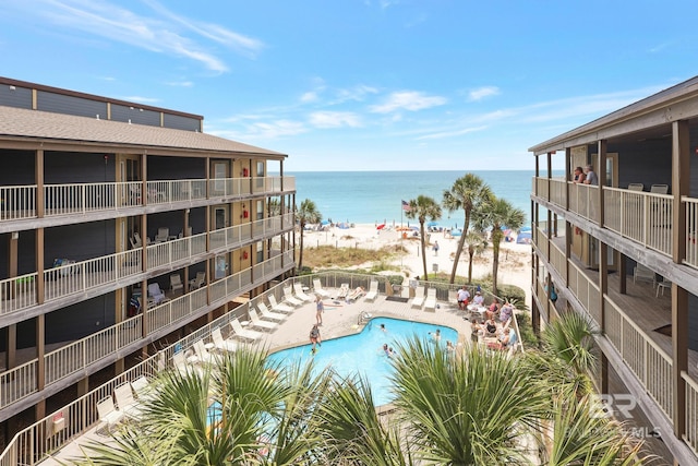 view of pool with a beach view, a water view, and a patio area