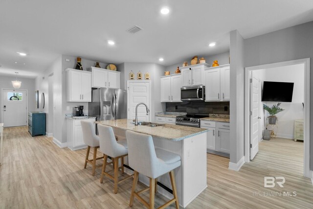 4175 Montague Dr, Gulf Shores, AL 36542 - kitchen featuring stainless steel appliances, a kitchen breakfast bar, white cabinetry, tasteful backsplash, and recessed lighting