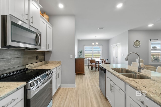 4175 Montague Dr, Gulf Shores, AL 36542 - kitchen with stainless steel appliances, light wood-style floors, white cabinetry, healthy amount of natural light, and recessed lighting