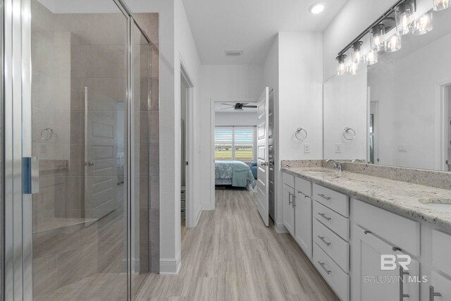 4175 Montague Dr, Gulf Shores, AL 36542 - ensuite bathroom with double vanity, a stall shower, a ceiling fan, wood finished floors, and recessed lighting