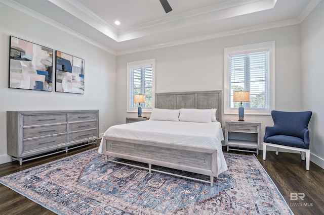 bedroom featuring a tray ceiling, dark wood-type flooring, ornamental molding, and ceiling fan