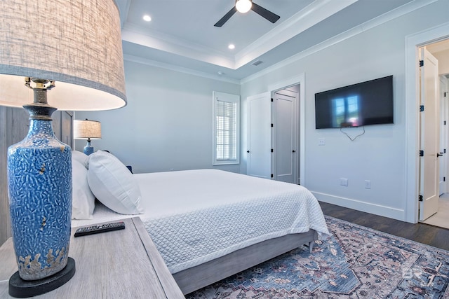 bedroom with dark wood-type flooring, ceiling fan, a tray ceiling, and crown molding