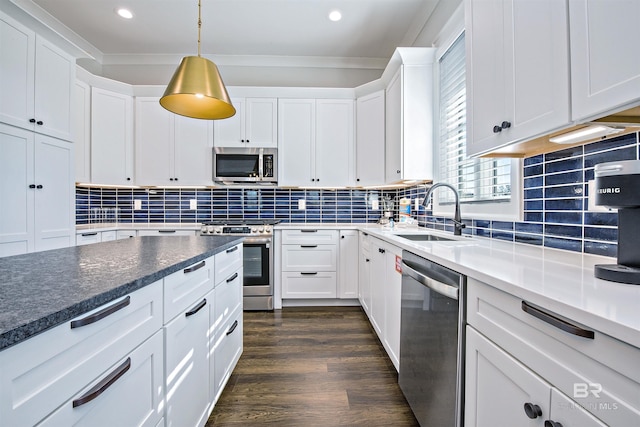 kitchen with stainless steel appliances, white cabinetry, hanging light fixtures, and sink