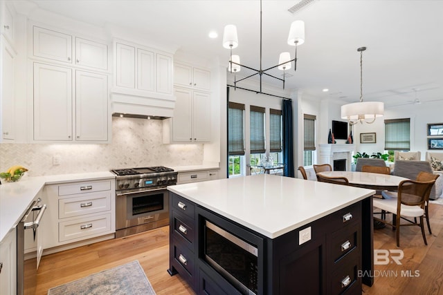 kitchen featuring stainless steel appliances, white cabinets, light hardwood / wood-style floors, and tasteful backsplash