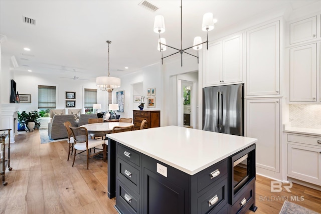 kitchen featuring pendant lighting, stainless steel appliances, light hardwood / wood-style flooring, and white cabinetry