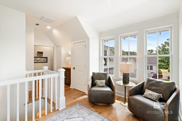 interior space with vaulted ceiling, a crib, and light hardwood / wood-style floors