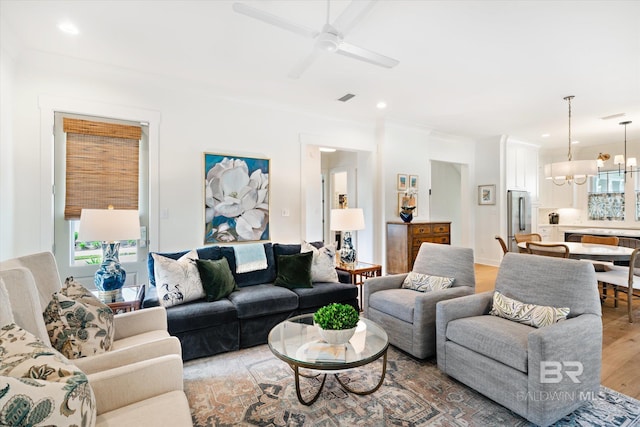 living room with ceiling fan with notable chandelier and hardwood / wood-style floors