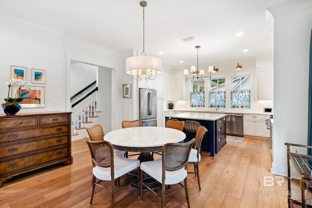 dining room featuring a notable chandelier, sink, light wood-type flooring, and crown molding