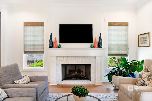 living room with crown molding, a tiled fireplace, and light wood-type flooring