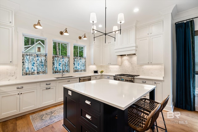 kitchen featuring light hardwood / wood-style floors, tasteful backsplash, decorative light fixtures, stove, and sink