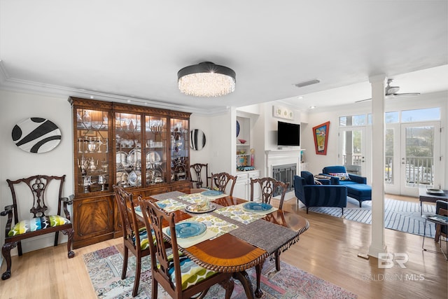dining room featuring visible vents, crown molding, a fireplace, wood finished floors, and ceiling fan