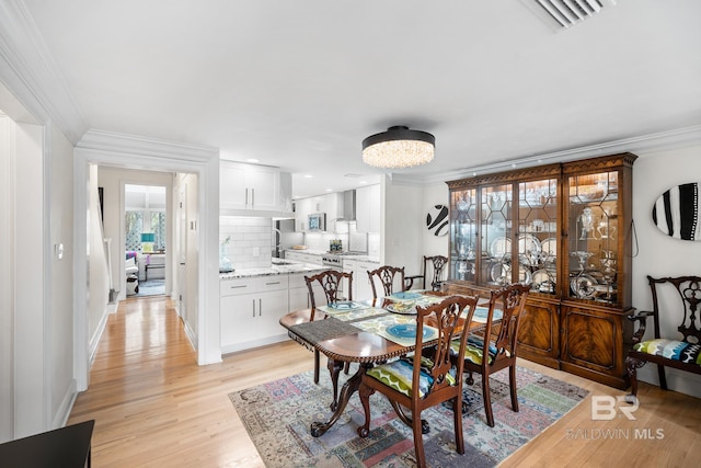 dining space featuring baseboards, ornamental molding, visible vents, and light wood finished floors