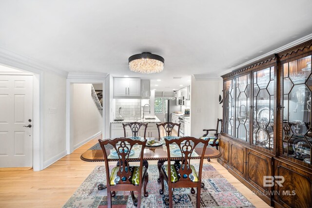 dining room with crown molding, baseboards, and light wood-type flooring