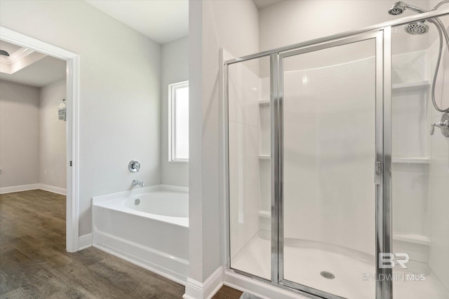 bathroom with a shower stall, a garden tub, wood finished floors, and baseboards
