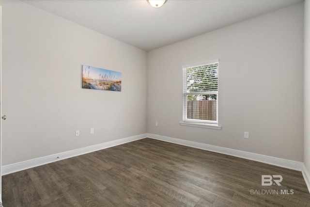 empty room featuring dark wood finished floors and baseboards