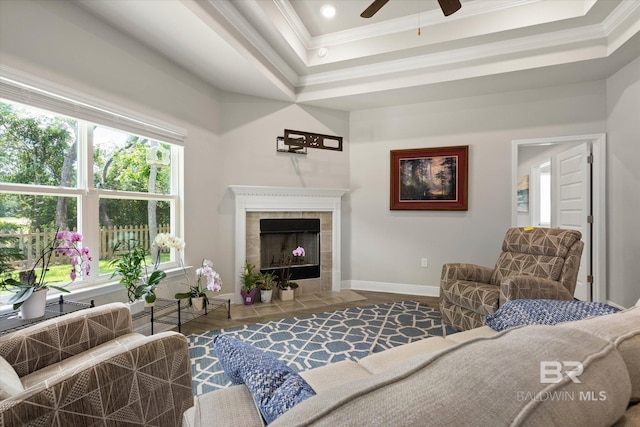 living room featuring ornamental molding, a tray ceiling, a ceiling fan, wood finished floors, and baseboards