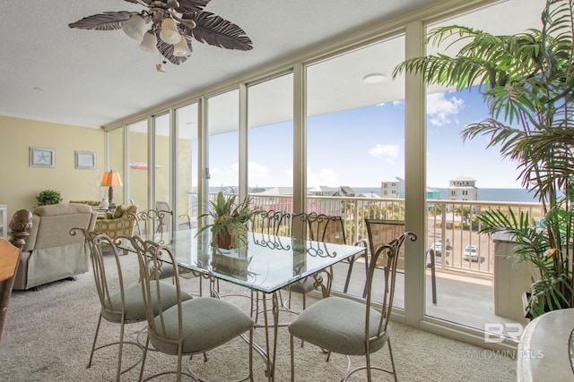 sunroom / solarium featuring ceiling fan, a water view, and a healthy amount of sunlight