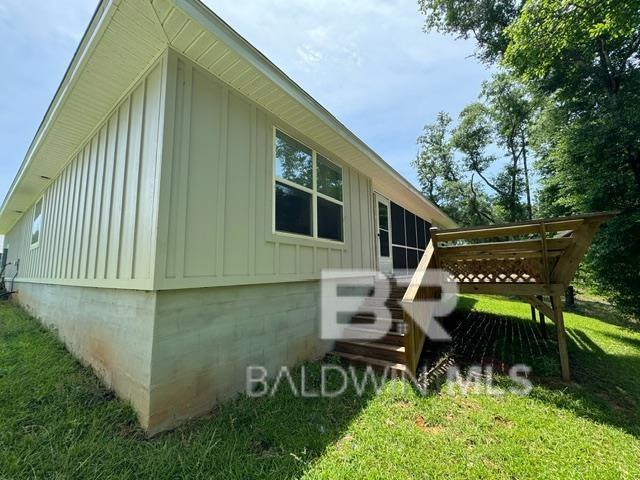 32807 N Pickens Ave, Lillian, AL 36549 - view of home's exterior featuring board and batten siding, a lawn, and a deck