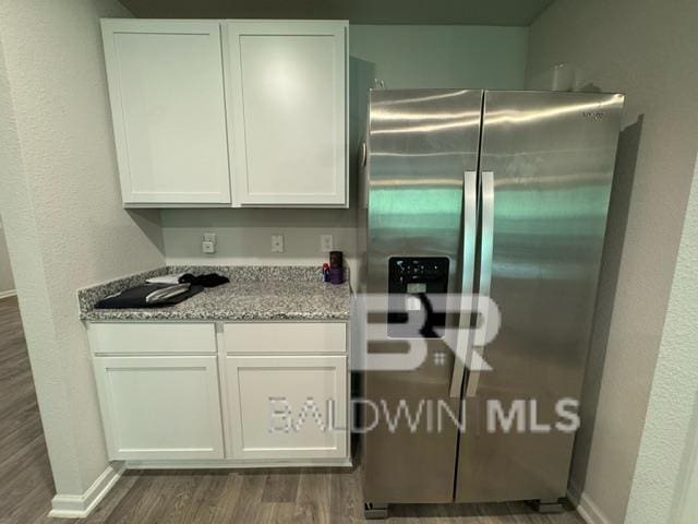 32807 N Pickens Ave, Lillian, AL 36549 - kitchen with stainless steel fridge with ice dispenser, dark wood-type flooring, white cabinets, and light stone counters