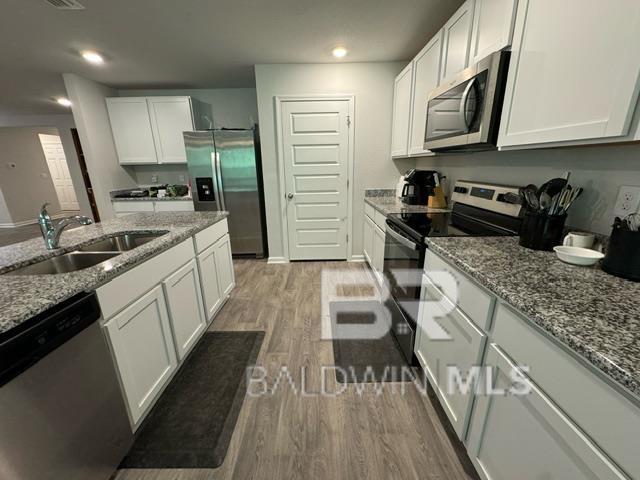 32807 N Pickens Ave, Lillian, AL 36549 - kitchen with appliances with stainless steel finishes, a sink, light wood-style flooring, white cabinetry, and recessed lighting
