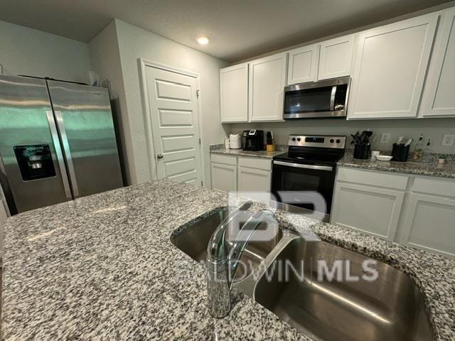 32807 N Pickens Ave, Lillian, AL 36549 - kitchen featuring appliances with stainless steel finishes, white cabinetry, stone countertops, and recessed lighting