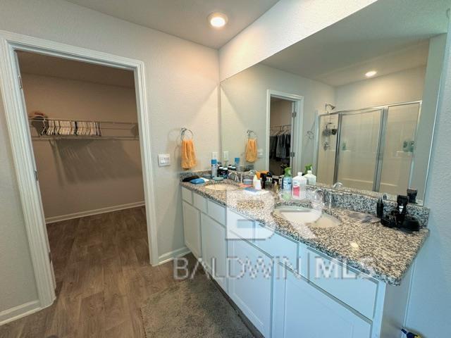 32807 N Pickens Ave, Lillian, AL 36549 - full bath featuring a spacious closet, wood finished floors, double vanity, a stall shower, and baseboards