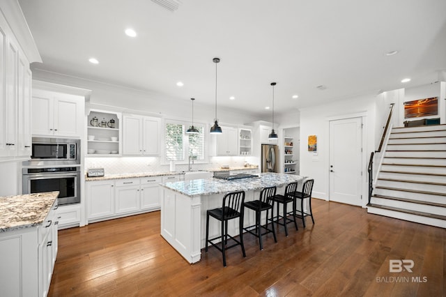 kitchen featuring appliances with stainless steel finishes, a center island, hardwood / wood-style floors, and white cabinets