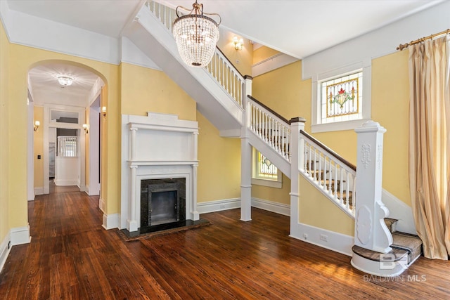 251 S Georgia Ave, Mobile, AL 36604 - unfurnished living room featuring stairs, hardwood / wood-style flooring, arched walkways, baseboards, and a notable chandelier