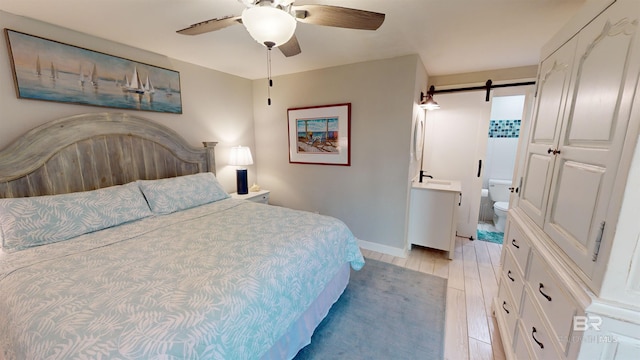 511 E Beach Blvd Unit 503, Gulf Shores, AL 36542 - bedroom with a barn door, light wood-style flooring, baseboards, and ceiling fan