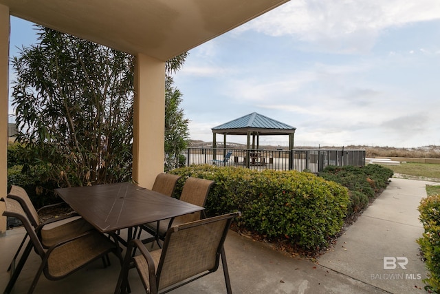 view of patio featuring a gazebo, outdoor dining space, and fence